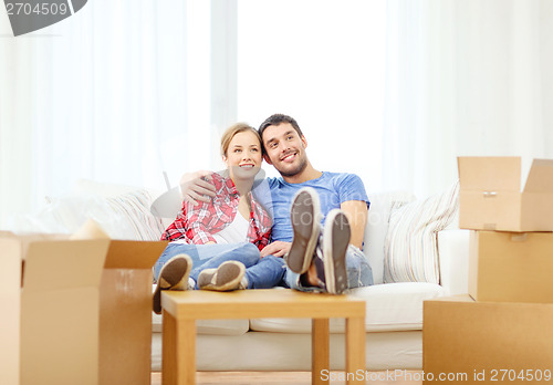 Image of smiling couple relaxing on sofa in new home