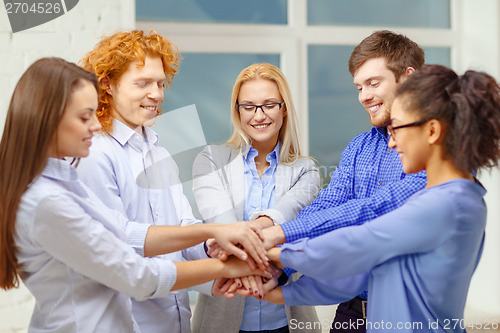 Image of team with hands on top of each other in office