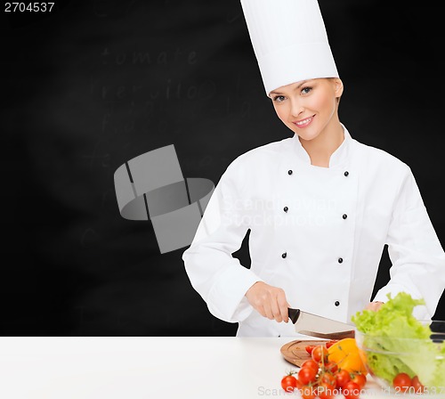 Image of smiling female chef chopping vagetables