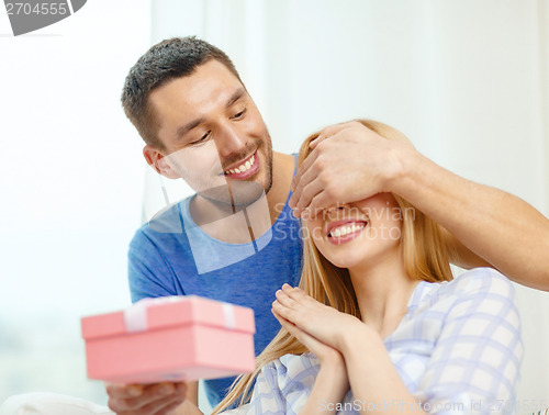 Image of smiling man surprises his girlfriend with present