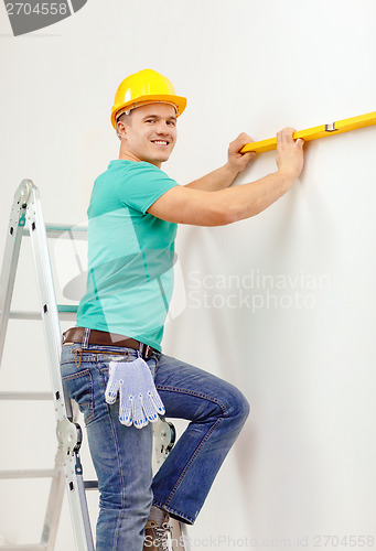 Image of smiling man building using spirit level to measure