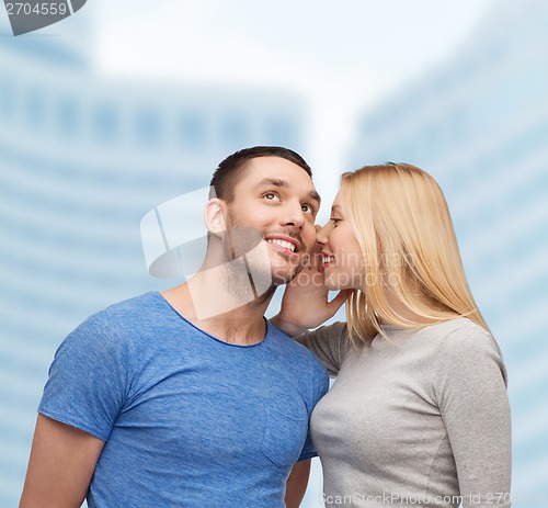 Image of smiling girlfriend telling boyfriend secret