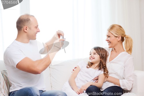 Image of happy father taking picture of mother and daughter