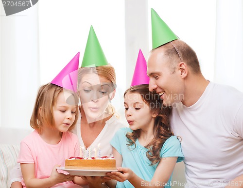 Image of smiling family with two kids in hats with cake