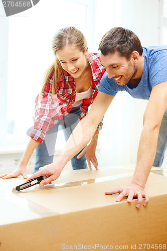 Image of smiling couple opening big cardboard box