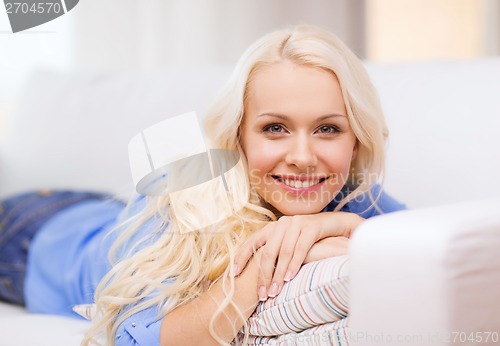 Image of smiling young woman lying on sofa at home