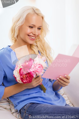 Image of smiling woman with card and bouquet of flowers