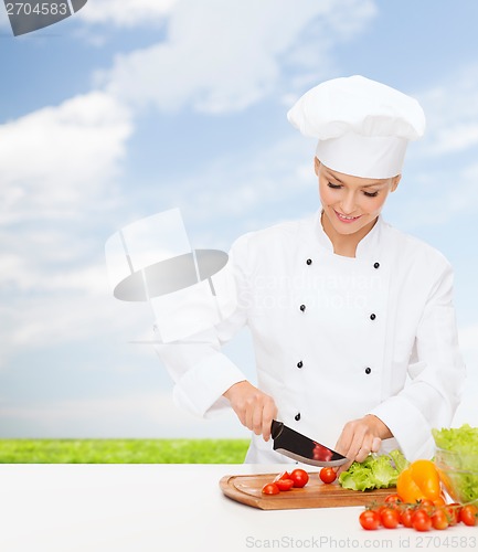 Image of smiling female chef chopping vagetables