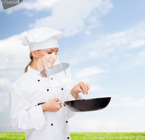 Image of smiling female chef with pan and spoon