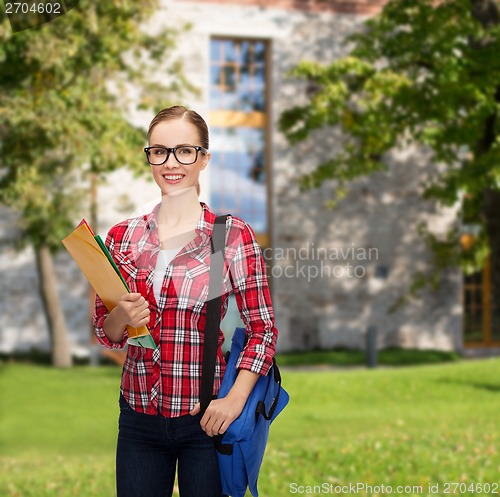 Image of female student in eyeglasses with bag and folders