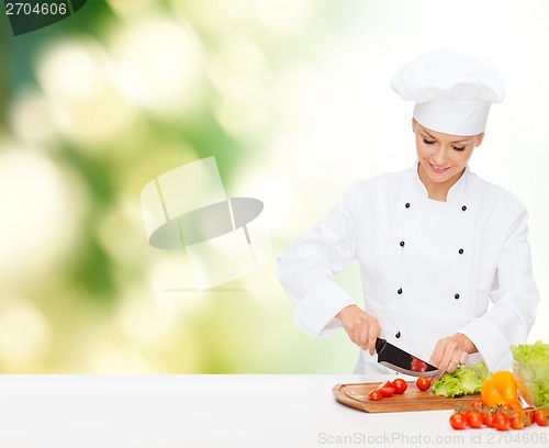 Image of smiling female chef chopping vagetables