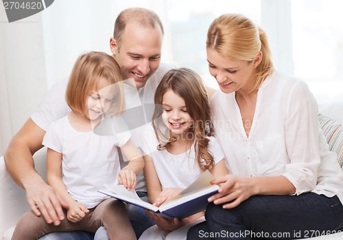 Image of smiling family and two little girls with book