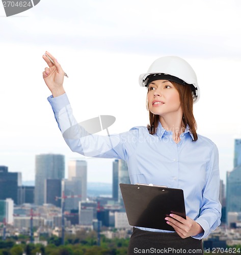 Image of smiling businesswoman in helmet with clipboard