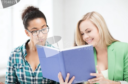 Image of smiling student girls reading book at school