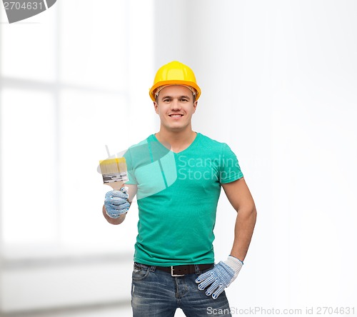 Image of smiling manual worker in helmet with paintbrush