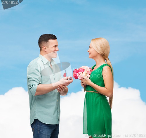 Image of smiling couple with flower bouquet and ring