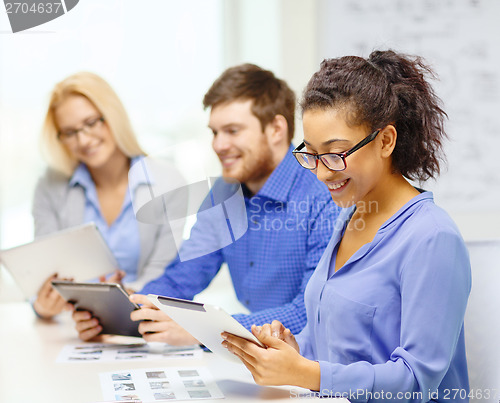 Image of smiling team with table pc and papers working