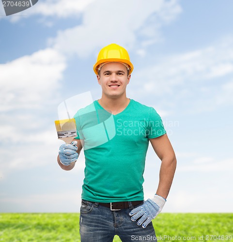 Image of smiling manual worker in helmet with paintbrush