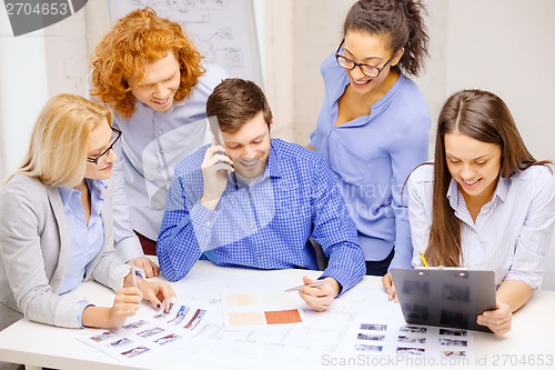 Image of creative team with papers and clipboard at office