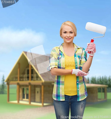 Image of smiling woman in gloves with paint roller