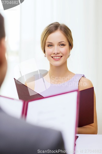 Image of smiling young woman with menu at restaurant