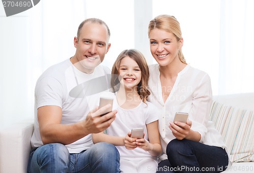Image of parents and little girl with smartphones at home
