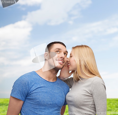 Image of smiling girlfriend telling boyfriend secret