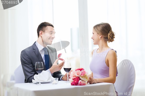 Image of man proposing to his girlfriend at restaurant