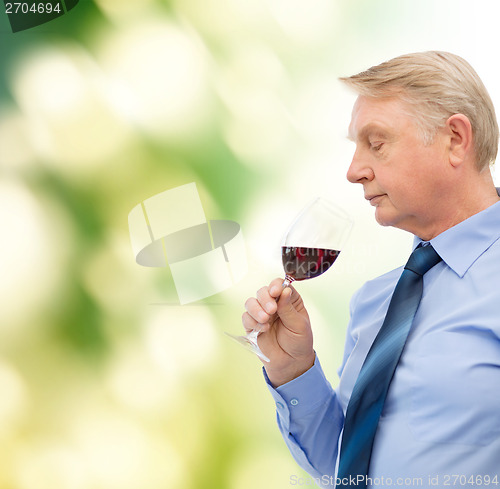 Image of elderly man smelling red wine