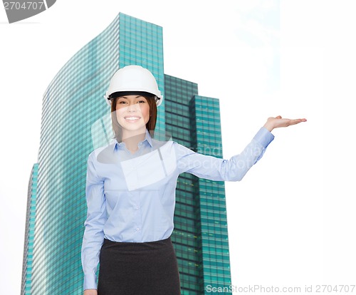 Image of businesswoman in helmet holding something on palm