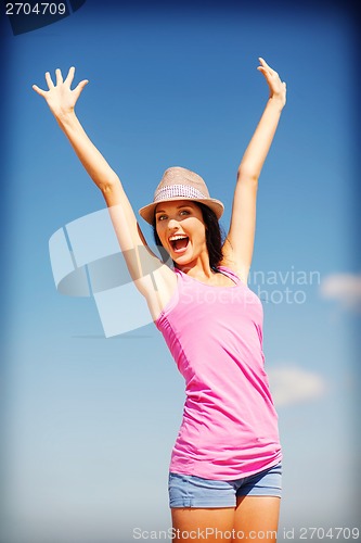 Image of girl with hands up on the beach