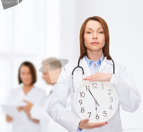 Image of calm female doctor with wall clock