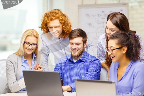 Image of smiling team with laptop computers in office