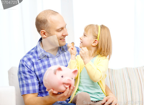 Image of happy father and daughter with big piggy bank