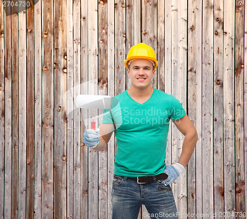 Image of smiling manual worker in helmet with paint roller