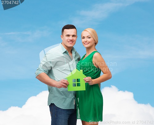 Image of smiling couple holding green paper house