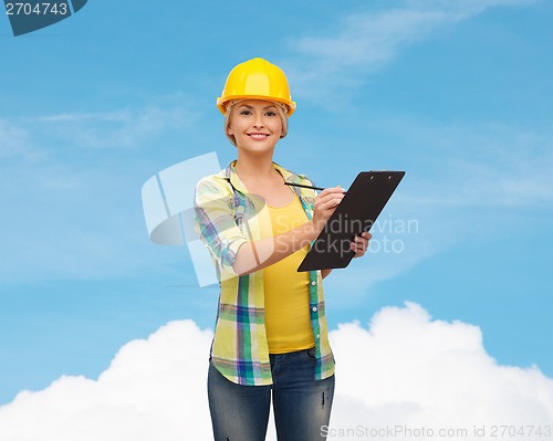 Image of smiling woman in helmet with clipboard