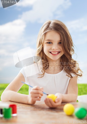 Image of smiling little girl coloring eggs for easter