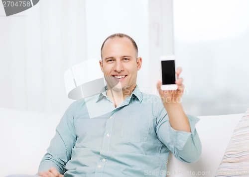 Image of smiling man with smartphone at home