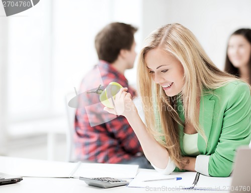 Image of smiling student girl eating apple at school