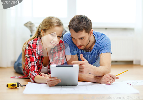 Image of smiling couple looking at tablet pc at home
