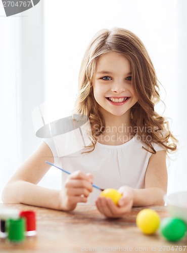 Image of smiling little girl coloring eggs for easter