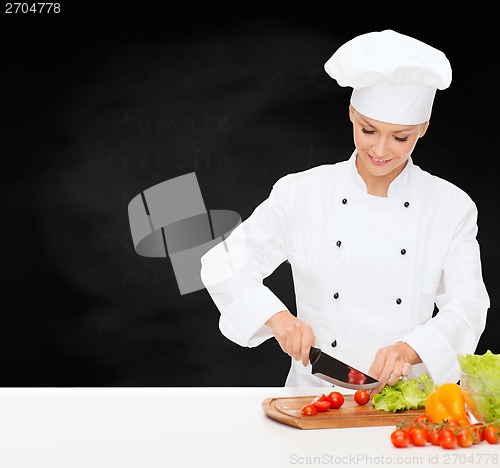 Image of smiling female chef chopping vagetables