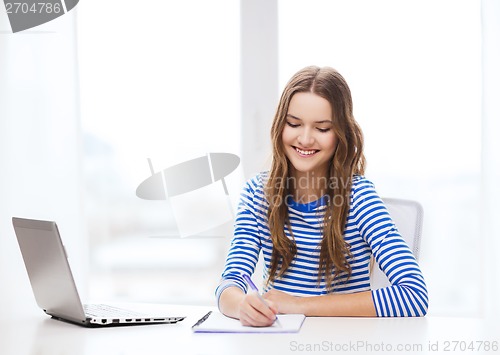 Image of smiling teenage girl laptop computer and notebook