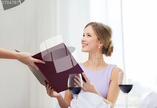 Image of smiling woman recieving menu from waiter