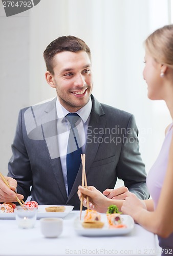 Image of smiling couple eating sushi at restaurant