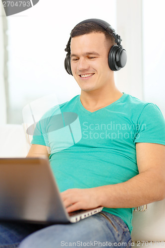 Image of smiling man with laptop and headphones at home