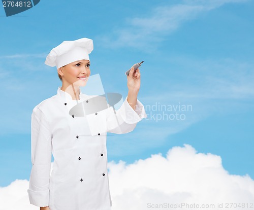 Image of smiling female chef writing something on air