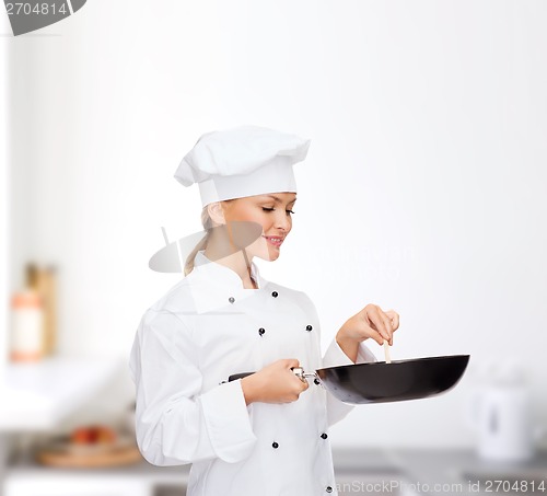 Image of smiling female chef with pan and spoon