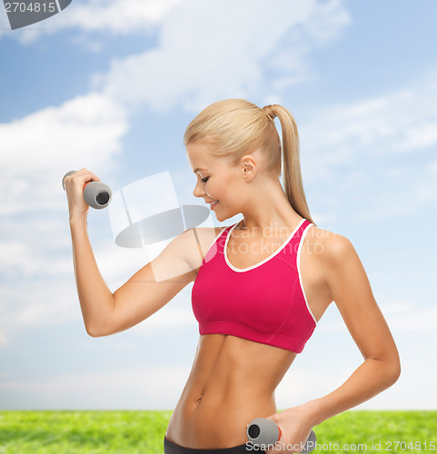 Image of young sporty woman with light dumbbells outdoors